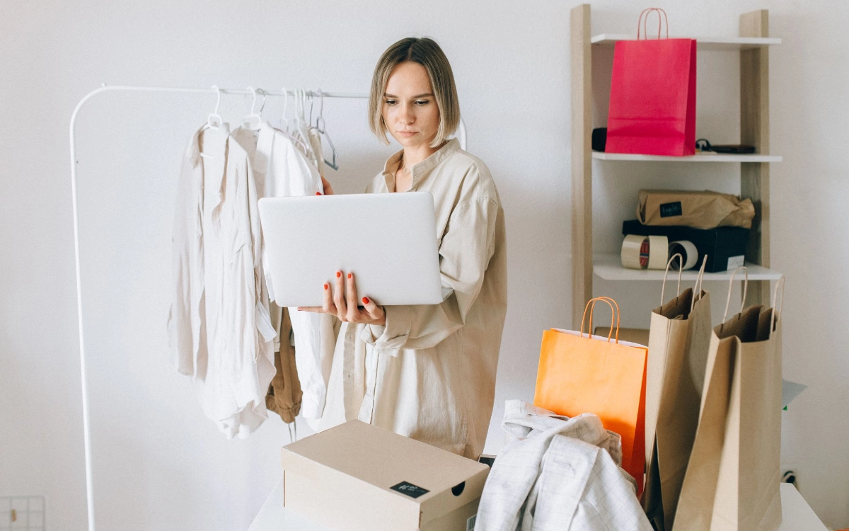 Woman sitting on a bed, reading a Kindle, and decluttering.